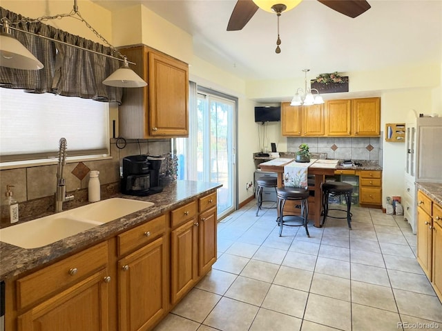 4383 S Eagle Cir, Aurora, CO 80015 - kitchen with a sink, backsplash, brown cabinets, ceiling fan, and light tile patterned floors