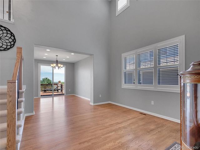 2485 Greensborough Cir, Highlands Ranch, CO 80129 - unfurnished living room with a chandelier, stairs, light wood finished floors, and a towering ceiling