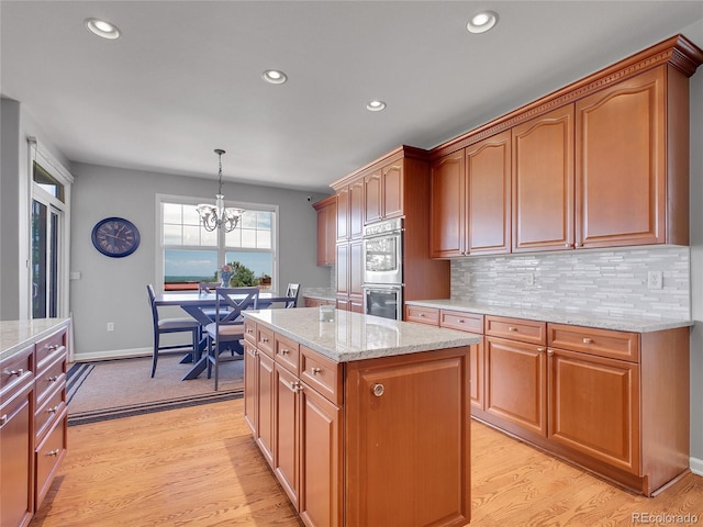 2485 Greensborough Cir, Highlands Ranch, CO 80129 - kitchen with stainless steel double oven, light wood-type flooring, a chandelier, light stone counters, and recessed lighting