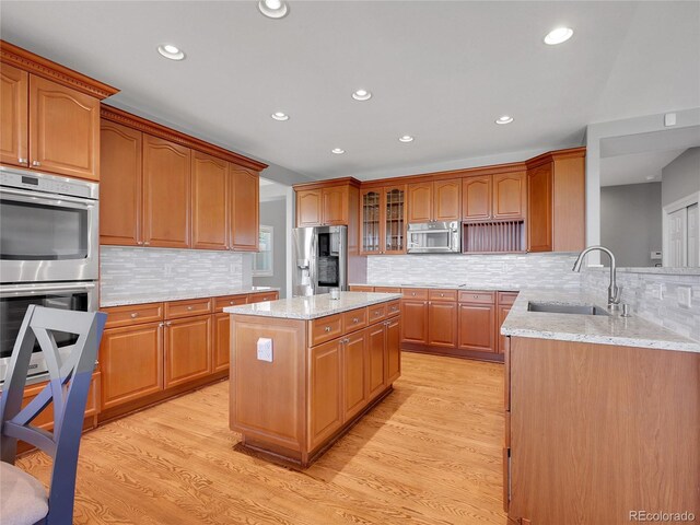 2485 Greensborough Cir, Highlands Ranch, CO 80129 - kitchen with appliances with stainless steel finishes, light stone counters, light wood-style flooring, decorative backsplash, and recessed lighting