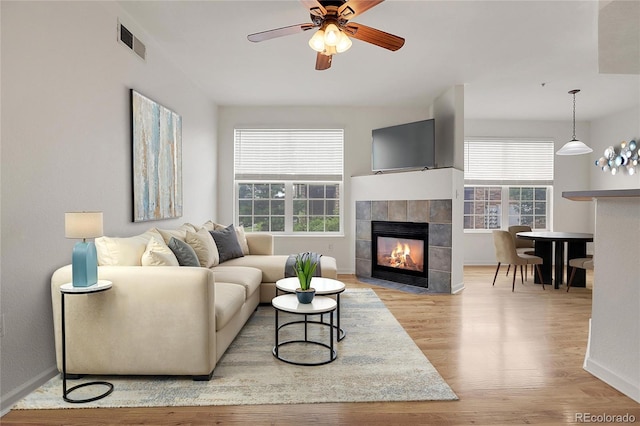 living room with ceiling fan, a fireplace, and light hardwood / wood-style flooring