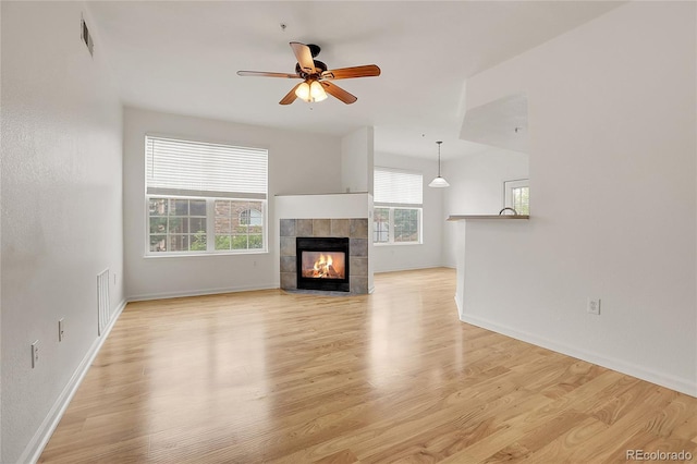 unfurnished living room with ceiling fan, light hardwood / wood-style floors, and a fireplace