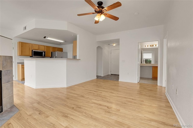 unfurnished living room with ceiling fan, a fireplace, and light hardwood / wood-style flooring