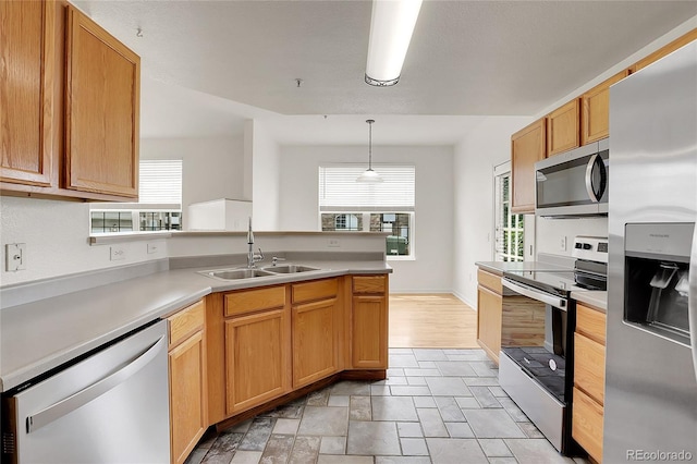 kitchen with decorative light fixtures, sink, appliances with stainless steel finishes, and kitchen peninsula