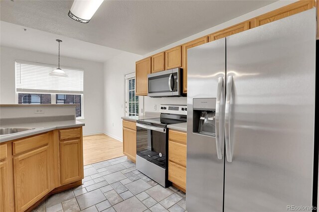 kitchen featuring decorative light fixtures, sink, light brown cabinets, and stainless steel appliances