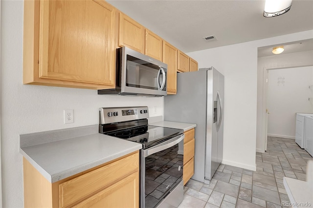 kitchen with washer and dryer, light brown cabinetry, and stainless steel appliances