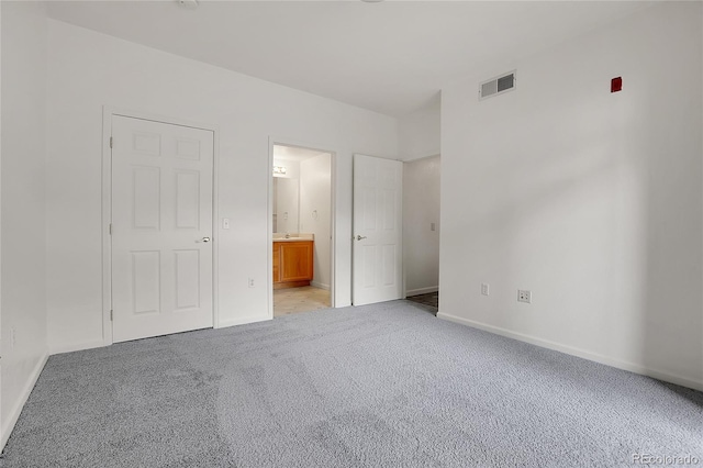 unfurnished bedroom with ensuite bathroom and light colored carpet