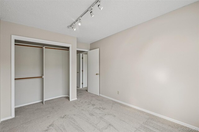 5849 Chokecherry Dr, Colorado Springs, CO 80919 - unfurnished bedroom featuring track lighting, a textured ceiling, carpet, baseboards, and a closet