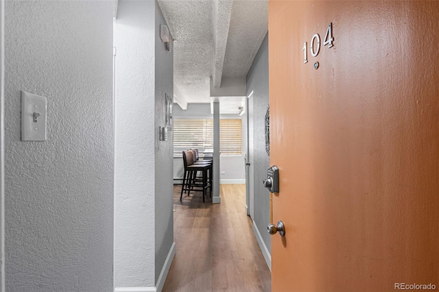 corridor with wood-type flooring and a textured ceiling