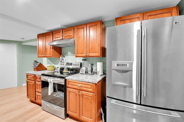 2580 Valley View Dr, Denver, CO 80221 - kitchen with stainless steel appliances, under cabinet range hood, light wood finished floors, light stone counters, and brown cabinets