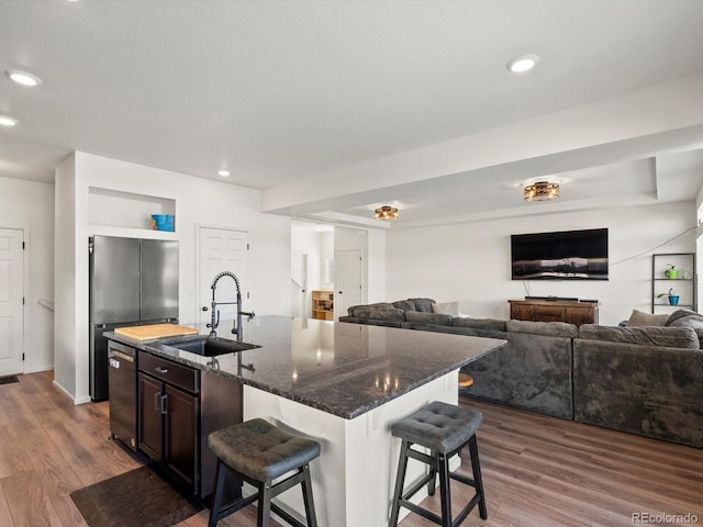 kitchen featuring an island with sink, a breakfast bar, sink, and dark stone countertops