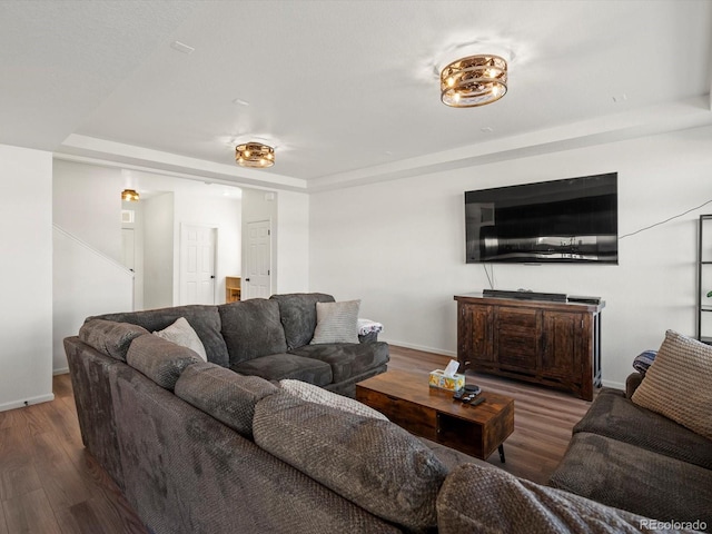 living room with dark wood-type flooring and a raised ceiling