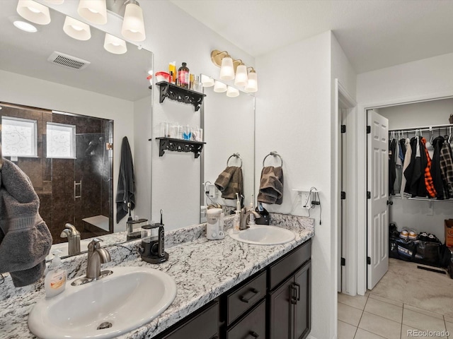 bathroom featuring vanity, tile patterned flooring, and a tile shower