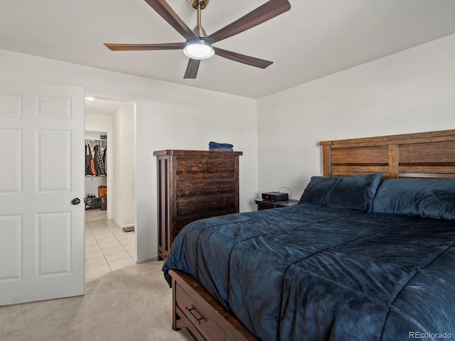 bedroom featuring light carpet, a spacious closet, and ceiling fan