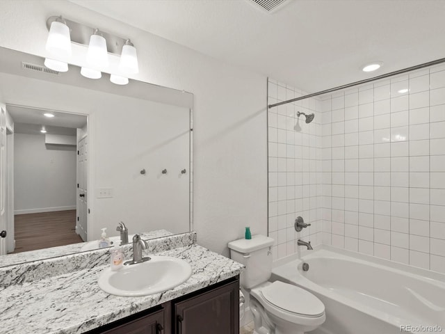 full bathroom with tiled shower / bath, vanity, and toilet