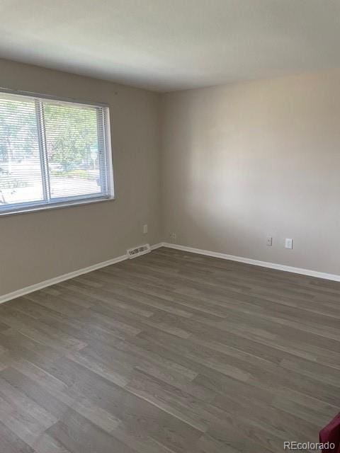 empty room featuring dark wood-style flooring and baseboards