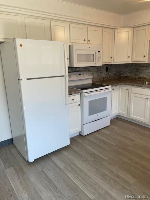 kitchen featuring white appliances, light wood-style floors, tasteful backsplash, and white cabinetry