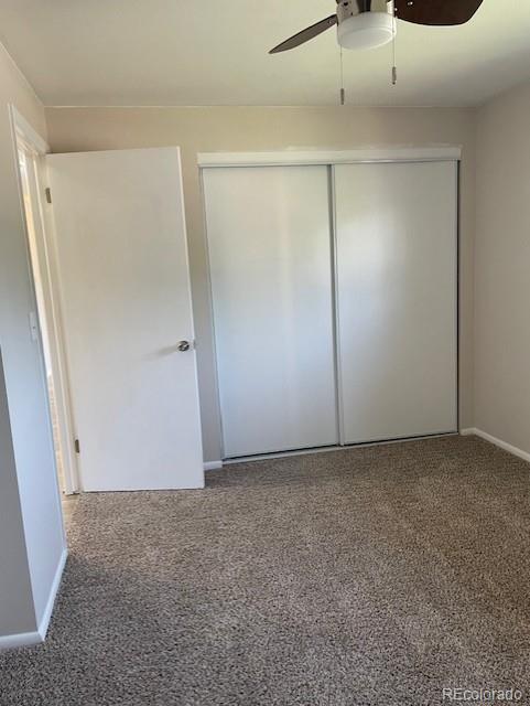 unfurnished bedroom featuring a closet, baseboards, ceiling fan, and carpet