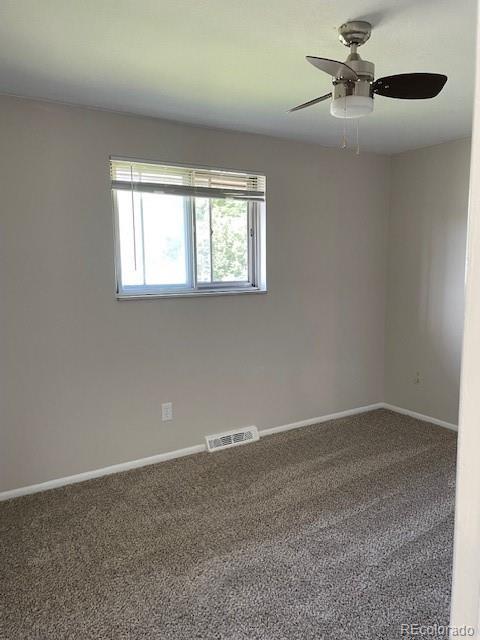 carpeted spare room featuring baseboards and ceiling fan