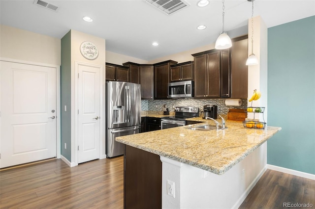 kitchen featuring dark brown cabinetry, appliances with stainless steel finishes, a sink, a peninsula, and visible vents