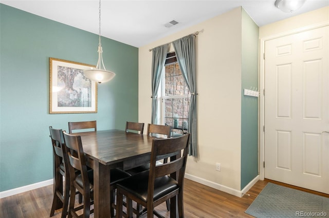 dining space featuring baseboards, wood finished floors, and visible vents