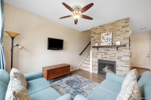 living room with ceiling fan, visible vents, wood finished floors, baseboards, and stairs