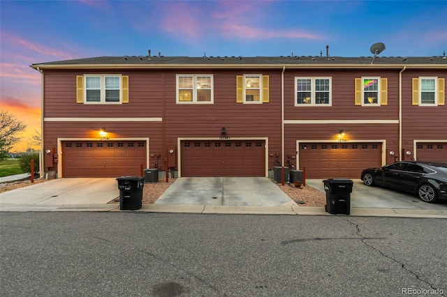 view of property featuring an attached garage, driveway, and central AC
