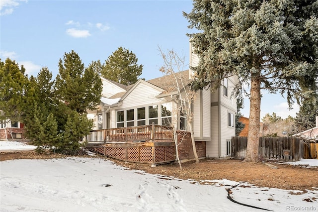 snow covered rear of property with a wooden deck