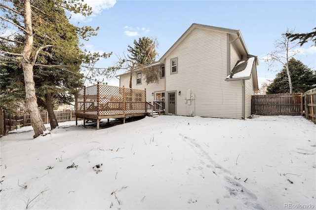 snow covered back of property with a deck