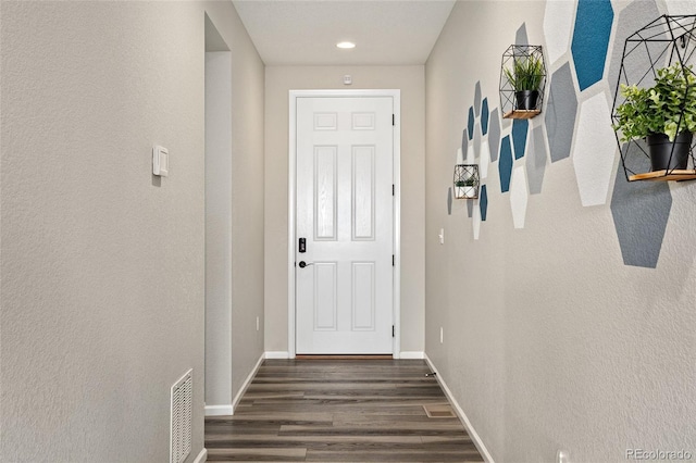 doorway with visible vents, baseboards, and dark wood finished floors