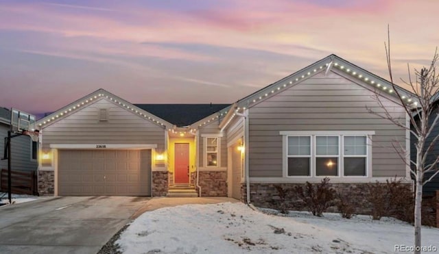 view of front facade with a garage, stone siding, concrete driveway, and entry steps