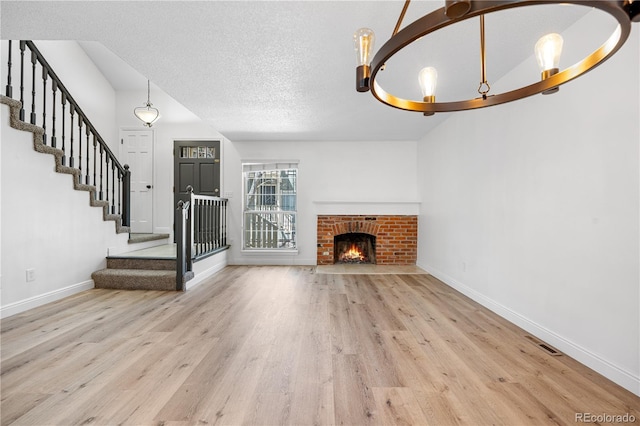 unfurnished living room with visible vents, wood finished floors, baseboards, and stairs