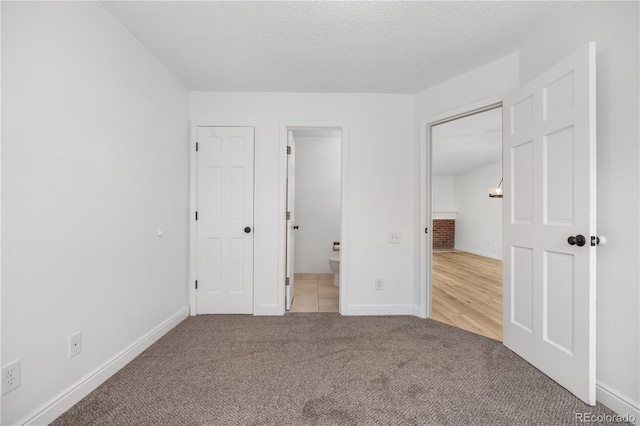 unfurnished bedroom featuring baseboards, ensuite bathroom, and carpet