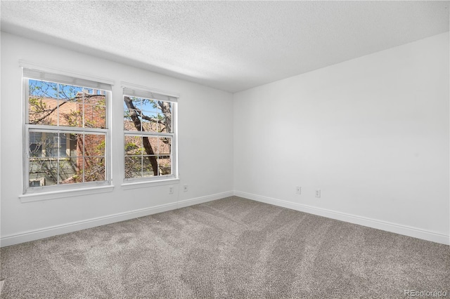 spare room with a textured ceiling, baseboards, and carpet floors