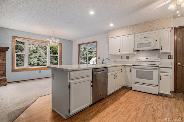 523 E Long Ct, Littleton, CO 80122 - kitchen with white appliances, a peninsula, a textured ceiling, plenty of natural light, and a chandelier
