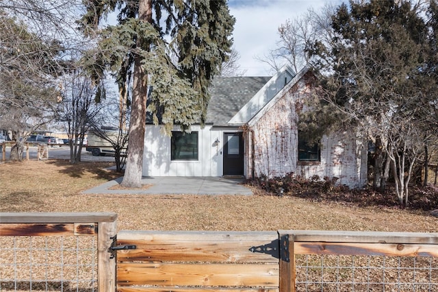 view of front of home featuring a fenced front yard, a patio area, board and batten siding, and roof with shingles