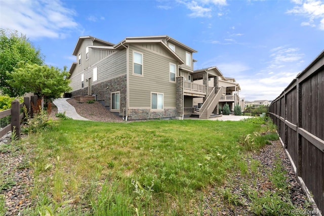 6129 E 143rd Ave, Thornton, CO 80602 - rear view of property with stone siding, board and batten siding, a fenced backyard, stairs, and a deck