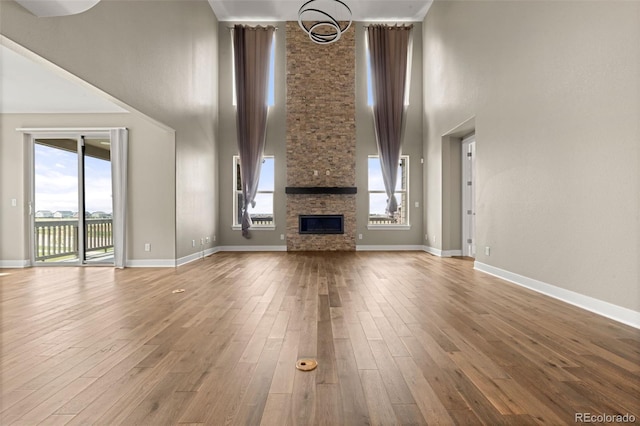 6129 E 143rd Ave, Thornton, CO 80602 - unfurnished living room with a high ceiling, a stone fireplace, and wood finished floors