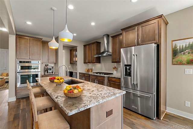 6129 E 143rd Ave, Thornton, CO 80602 - kitchen featuring appliances with stainless steel finishes, wall chimney exhaust hood, light stone counters, dark wood-style flooring, and recessed lighting