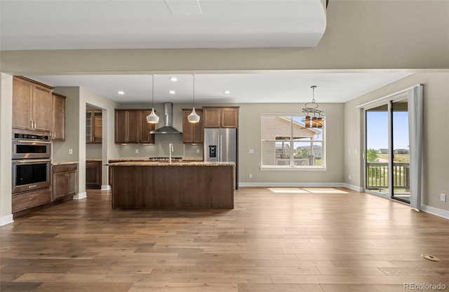 6129 E 143rd Ave, Thornton, CO 80602 - kitchen with appliances with stainless steel finishes, wall chimney range hood, dark wood finished floors, an island with sink, and recessed lighting