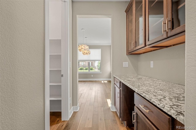 6129 E 143rd Ave, Thornton, CO 80602 - kitchen featuring wood finished floors, a chandelier, glass insert cabinets, light stone counters, and crown molding