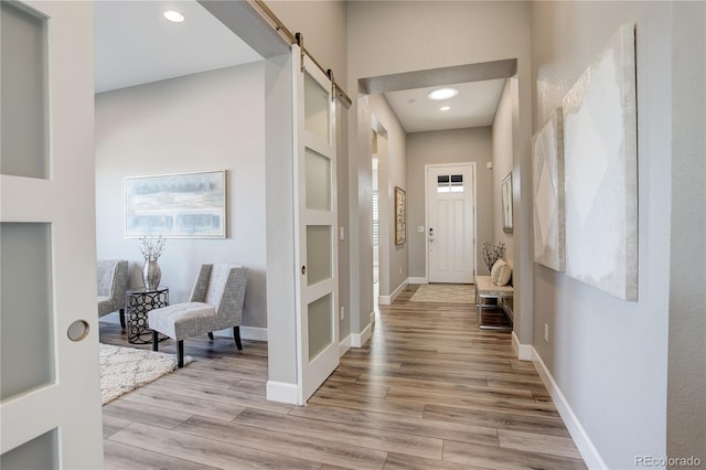 hall with a barn door, built in features, and light hardwood / wood-style flooring