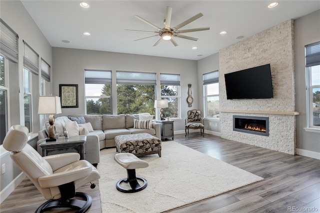 living room with a fireplace, light hardwood / wood-style flooring, and ceiling fan