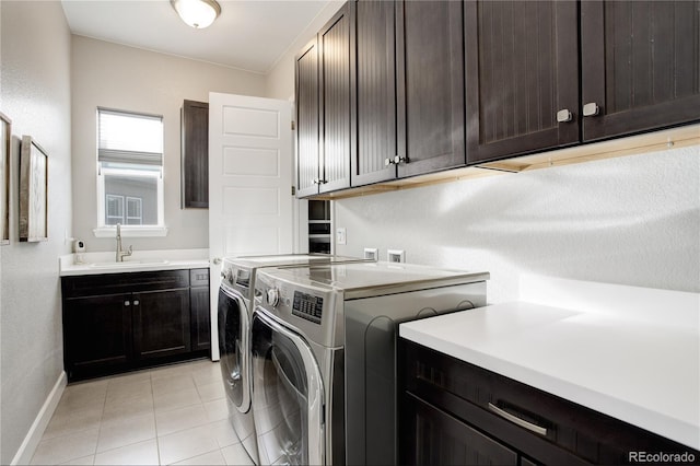 clothes washing area with washer and clothes dryer, sink, light tile patterned floors, and cabinets