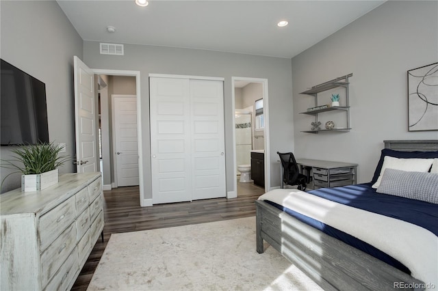 bedroom with ensuite bathroom, dark wood-type flooring, and a closet