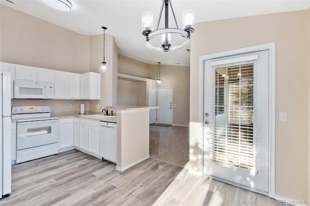 kitchen with kitchen peninsula, white appliances, pendant lighting, a notable chandelier, and white cabinets