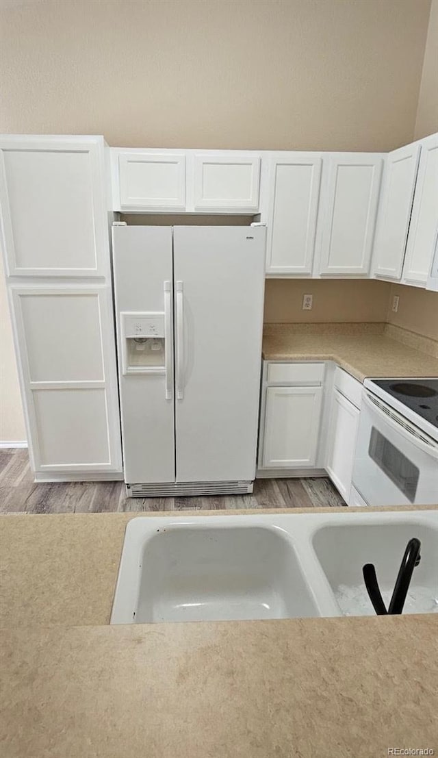 kitchen featuring white cabinetry, sink, white appliances, and light hardwood / wood-style flooring