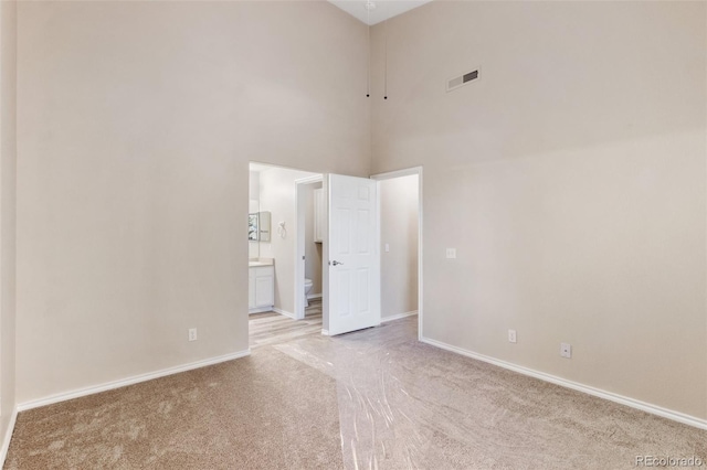 carpeted spare room with a towering ceiling