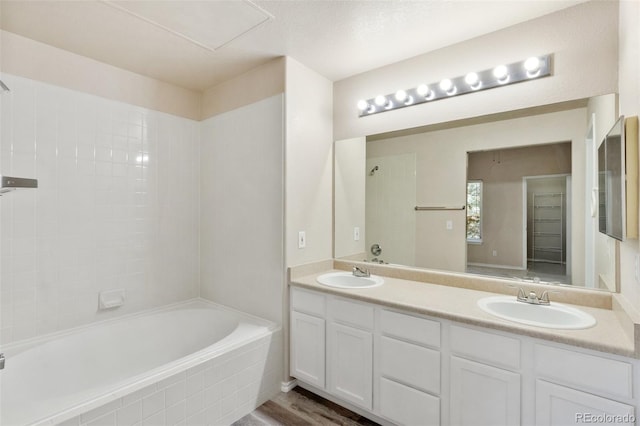 bathroom featuring vanity, wood-type flooring, and tiled shower / bath