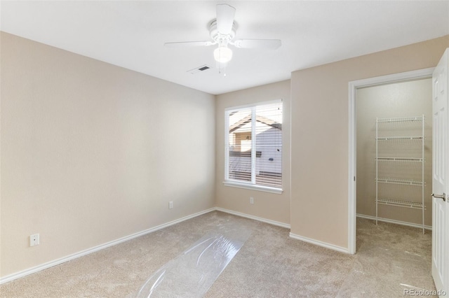 unfurnished bedroom featuring ceiling fan, a closet, a spacious closet, and light carpet